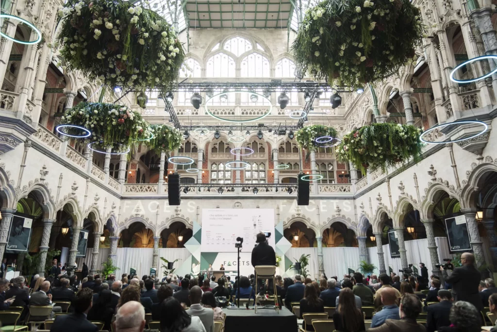 Prachtig ingericht evenement in een klassieke binnenplaats met kunstgroen op maat hangend van meerdere niveaus, omringd door ornamentale architectuur en publiek.